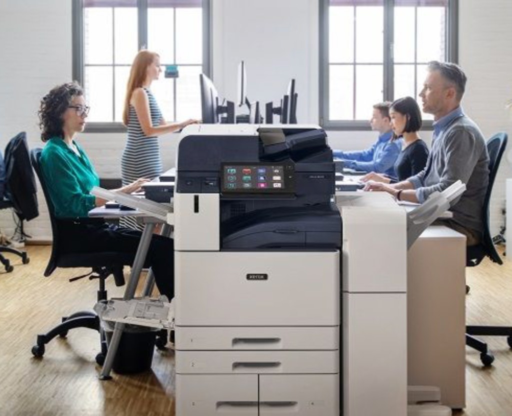 Office team working around a Xerox® AltaLink® C8145 multifunction printer in a modern workspace